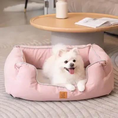 Thumbnail 400x400 for Perro blanco pequeño y esponjoso descansando en una cama ortopédica para perros de color rosa, con diseño ergonómico y bordes acolchados.