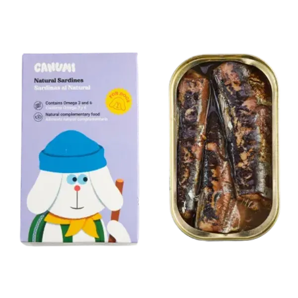 Lata abierta de sardinas naturales en conserva para perros junto a su empaque de la marca Canumi. El envase es de color lila con ilustración de un perro blanco con gorro azul y bufanda amarilla, destacando que el producto es un alimento complementario natural rico en Omega 3 y 6.