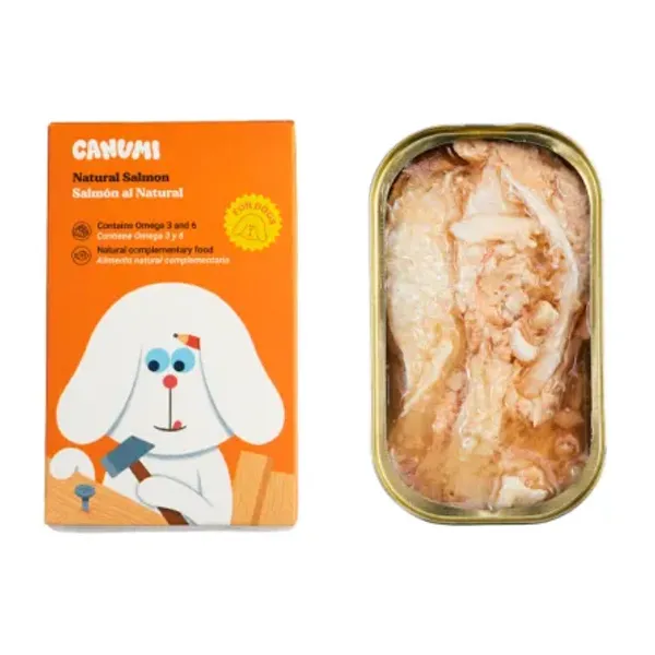  Lata abierta de salmón natural en conserva para perros junto a su empaque de la marca Canumi. El envase es de color naranja con una ilustración de un perro blanco con un martillo, destacando que el producto es un alimento complementario natural rico en Omega 3 y 6.