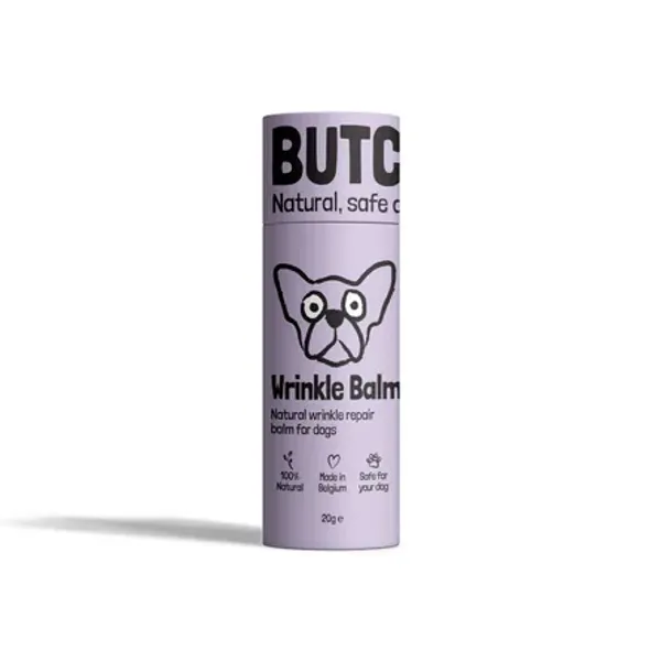 Envase cilíndrico lila de Wrinkle Balm para perros, un bálsamo natural diseñado para el cuidado de las arrugas. El diseño muestra ilustraciones y símbolos indicando que es 100% natural, hecho en Bélgica y seguro para los perros.